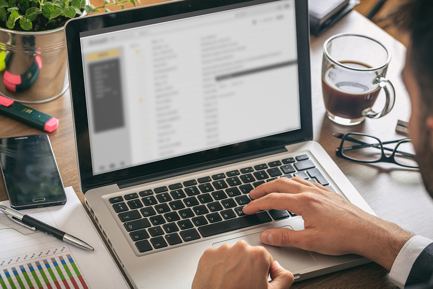 Emails list on a laptop screen, office background